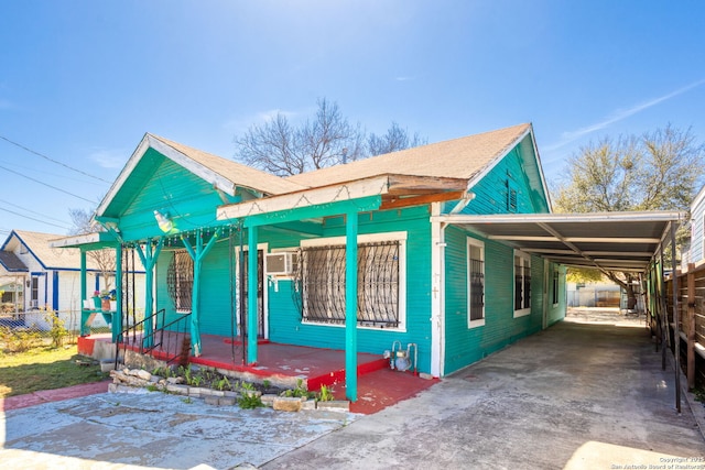 view of front of property featuring an attached carport, a porch, concrete driveway, and fence