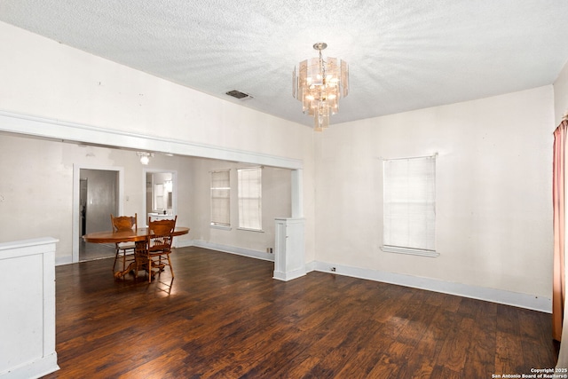 dining area with visible vents, baseboards, wood finished floors, a notable chandelier, and a textured ceiling