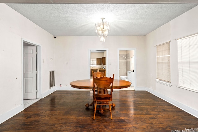 dining area featuring an inviting chandelier, wood finished floors, and a textured ceiling