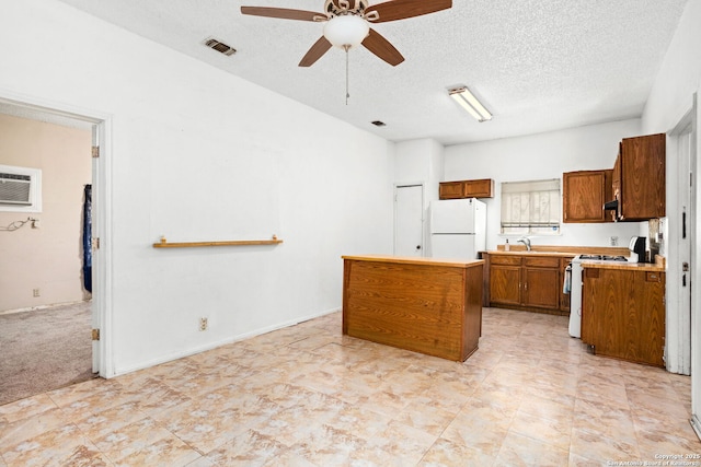 kitchen with white appliances, ceiling fan, light countertops, brown cabinets, and a center island