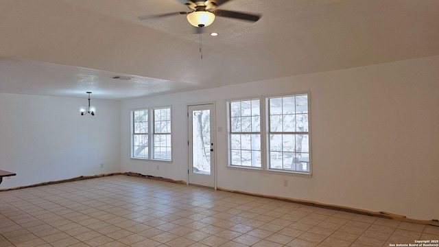 unfurnished room with visible vents, baseboards, ceiling fan with notable chandelier, light tile patterned flooring, and a textured ceiling