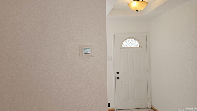 foyer featuring a tray ceiling and a textured wall