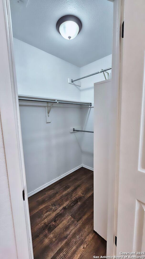 walk in closet with dark wood-type flooring