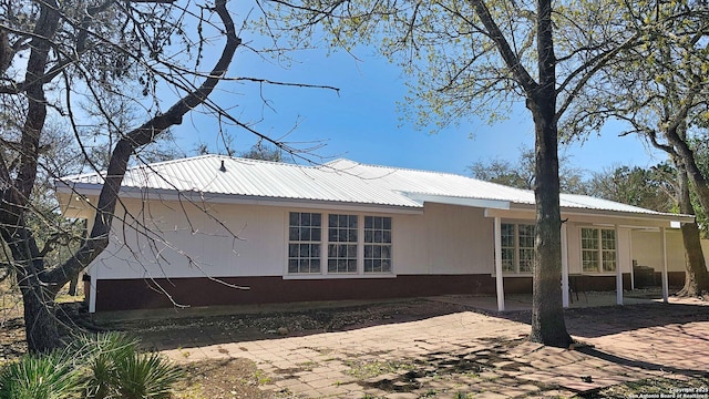 view of side of property featuring a patio area and metal roof