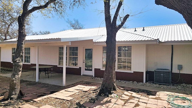 back of house with central air condition unit, metal roof, and a patio