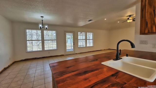 kitchen featuring light tile patterned flooring, visible vents, a textured ceiling, and a sink