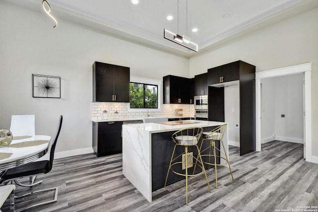 kitchen featuring light wood-style flooring, backsplash, stainless steel appliances, a center island, and recessed lighting