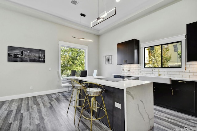 kitchen with light wood finished floors, a center island, a sink, and decorative backsplash