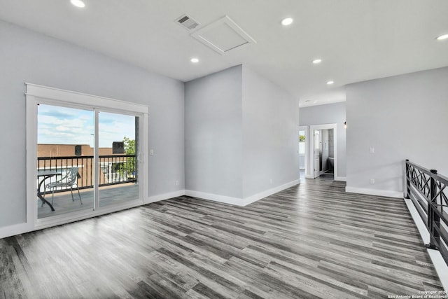 unfurnished living room with wood finished floors, baseboards, attic access, and recessed lighting