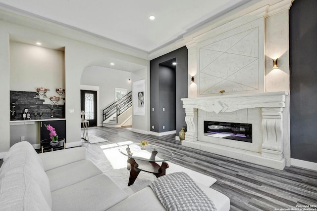 living room with baseboards, a fireplace, stairway, arched walkways, and wood finished floors