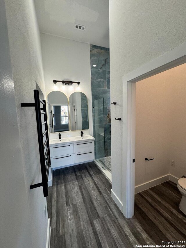full bath with a shower stall, wood finished floors, vanity, toilet, and baseboards