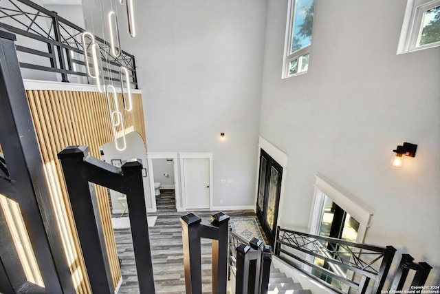 stairway with a high ceiling, baseboards, and wood finished floors