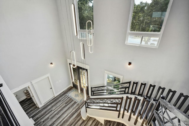 stairway with a towering ceiling, healthy amount of natural light, and wood finished floors