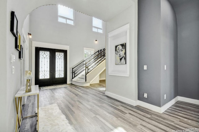 foyer entrance featuring stairs, plenty of natural light, wood finished floors, french doors, and a towering ceiling