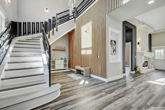 stairs with a high ceiling, wood finished floors, a high end fireplace, and baseboards