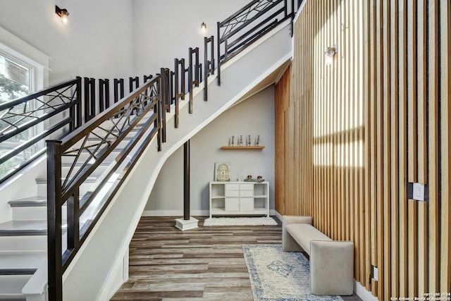 stairway featuring a high ceiling, wood finished floors, and baseboards