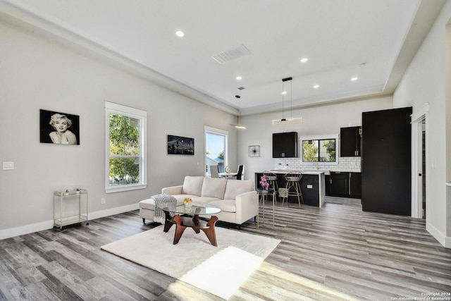 living room featuring light wood-style floors, plenty of natural light, recessed lighting, baseboards, and crown molding