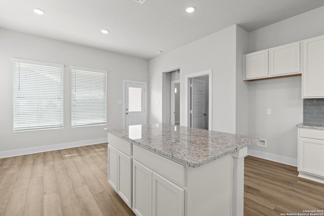 206 Buttercup Aly, San Antonio, TX 78253 - kitchen with a kitchen island, backsplash, light wood-style flooring, and white cabinetry