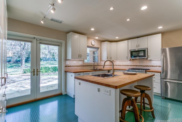 kitchen with visible vents, stainless steel appliances, white cabinets, dark floors, and wooden counters
