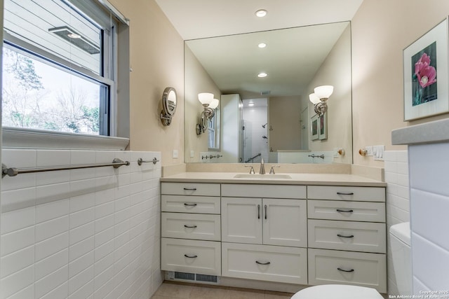 full bath featuring tile walls, toilet, recessed lighting, vanity, and a shower