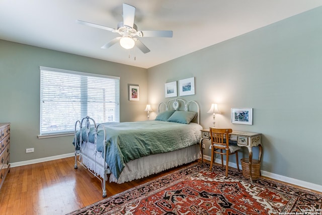 bedroom with hardwood / wood-style floors, a ceiling fan, and baseboards