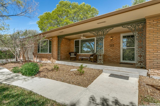 view of exterior entry with brick siding and covered porch