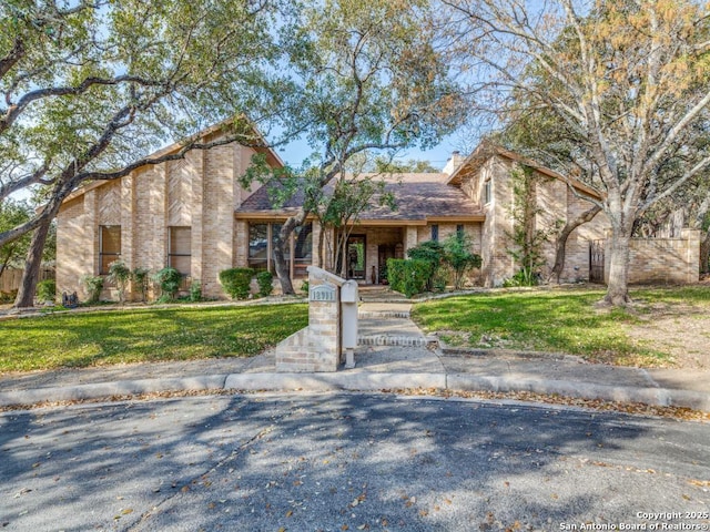 view of front of property with brick siding, a chimney, and a front lawn