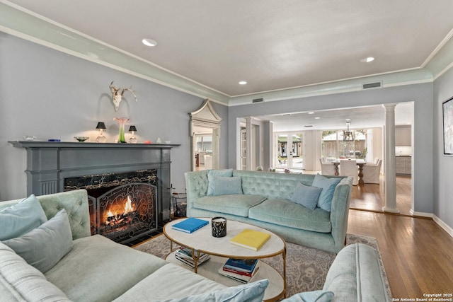 living area featuring visible vents, a fireplace with flush hearth, wood finished floors, and crown molding