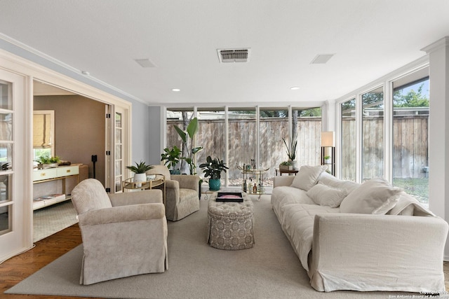 living room with ornamental molding, wood finished floors, visible vents, and expansive windows