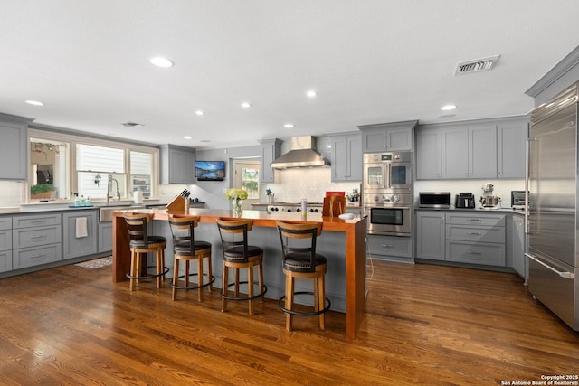 kitchen with stainless steel appliances, visible vents, gray cabinets, and wall chimney range hood