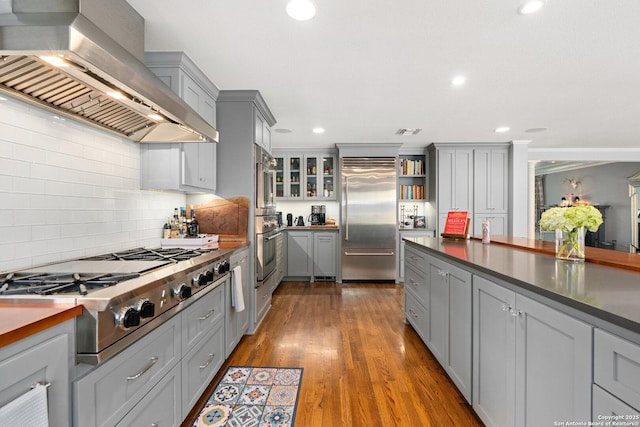 kitchen with dark wood-style flooring, appliances with stainless steel finishes, wall chimney exhaust hood, and gray cabinetry