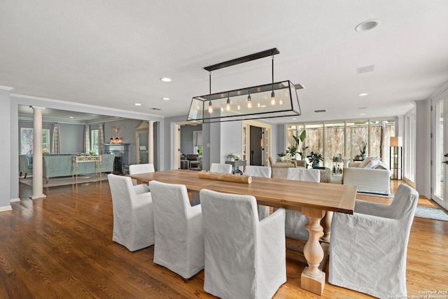 dining room featuring recessed lighting, a healthy amount of sunlight, wood finished floors, and ornate columns