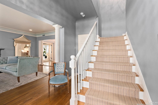 stairs featuring visible vents, wood finished floors, crown molding, decorative columns, and baseboards