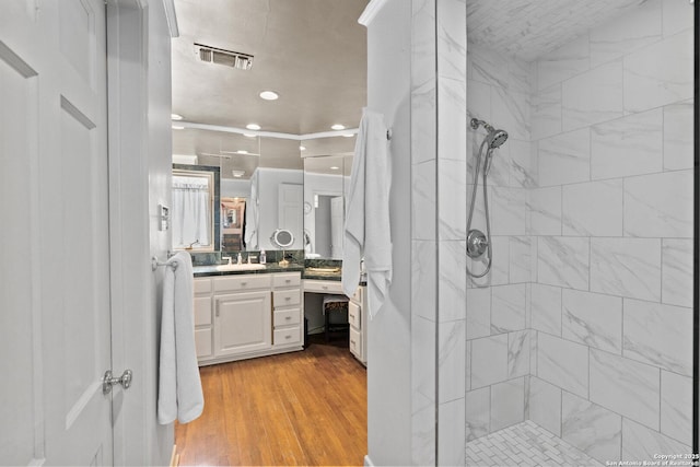 full bathroom with visible vents, wood finished floors, a tile shower, recessed lighting, and vanity