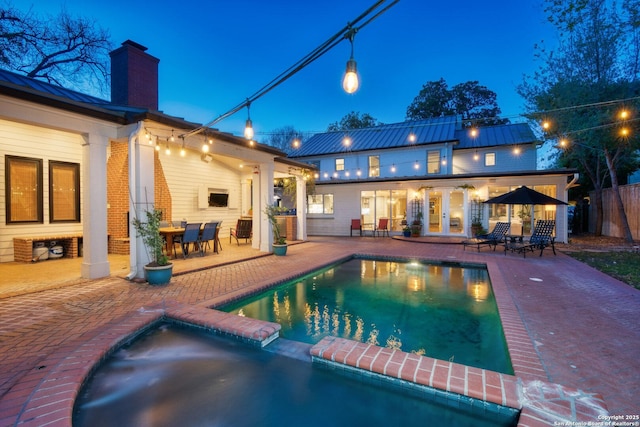 view of pool featuring french doors, a patio, fence, and a pool with connected hot tub