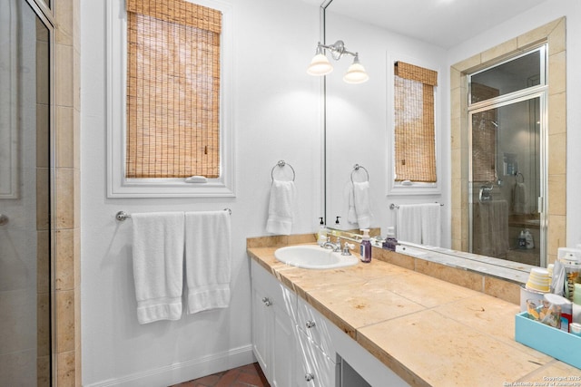 full bathroom with vanity, a shower stall, and baseboards