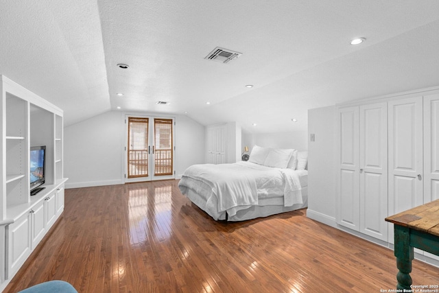 unfurnished bedroom featuring visible vents, baseboards, vaulted ceiling, hardwood / wood-style flooring, and a textured ceiling
