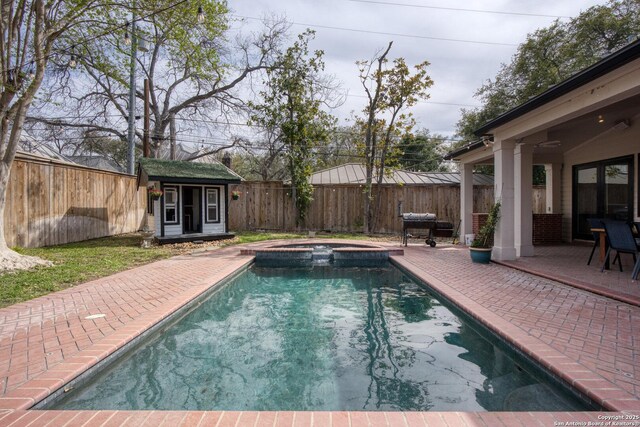 view of swimming pool with a patio area, a pool with connected hot tub, a fenced backyard, and an outdoor structure