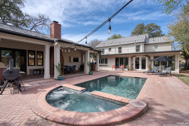 view of swimming pool with a patio area, french doors, a pool with connected hot tub, and a grill