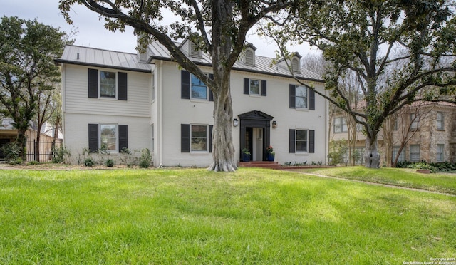 view of front facade featuring brick siding, a front lawn, a standing seam roof, and metal roof