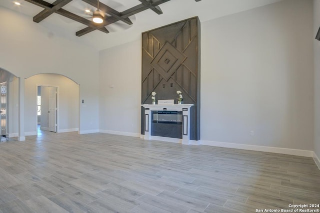 116 Hidden Ranch Ct, Floresville, TX 78114 - unfurnished living room with arched walkways, coffered ceiling, baseboards, beam ceiling, and light wood-style floors