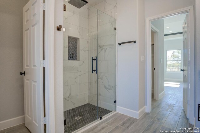 116 Hidden Ranch Ct, Floresville, TX 78114 - bathroom with a marble finish shower, baseboards, and wood finish floors