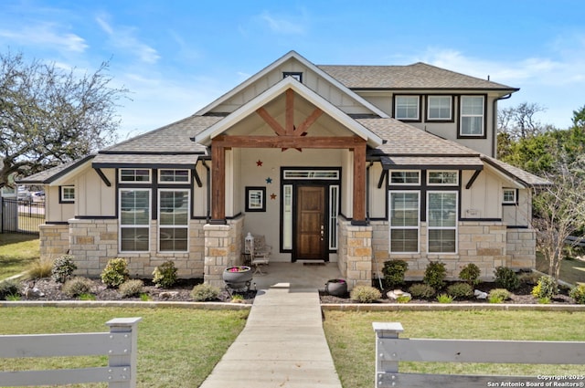 view of front of home featuring stone siding, board and batten siding, roof with shingles, and fence