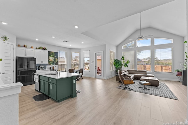 kitchen with green cabinets, black refrigerator, light wood-type flooring, light countertops, and a sink