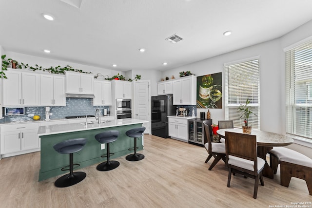 kitchen with visible vents, a sink, stainless steel appliances, white cabinets, and a kitchen bar