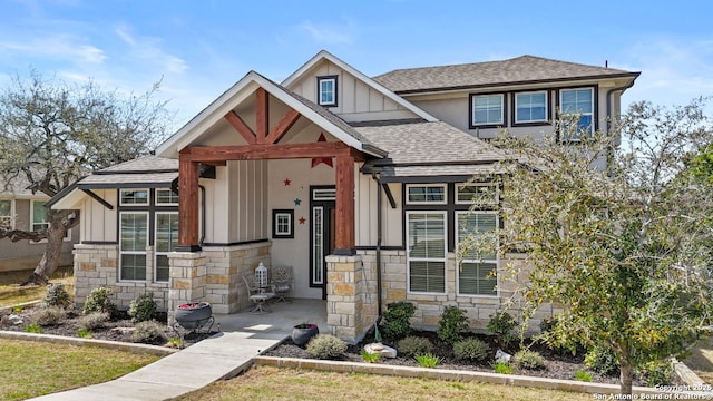 view of front of house with stone siding, board and batten siding, and roof with shingles