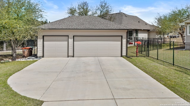 view of front of property featuring fence, a front yard, roof with shingles, driveway, and an attached garage