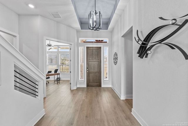 entryway featuring visible vents, baseboards, wood finished floors, and ceiling fan with notable chandelier