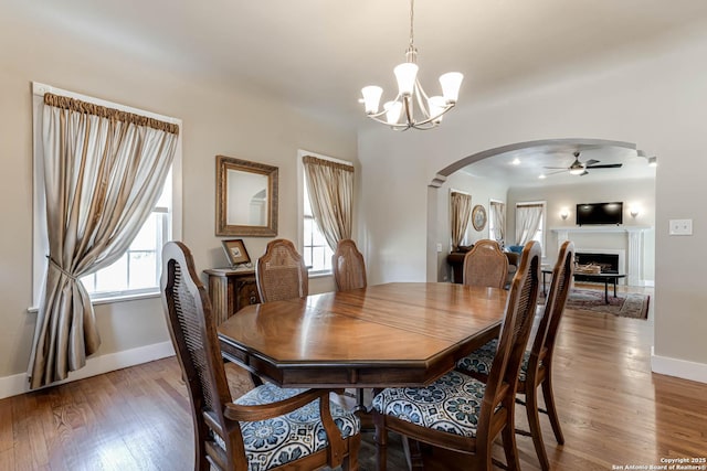2106 W Gramercy Pl, San Antonio, TX 78201 - dining space featuring ceiling fan with notable chandelier, wood finished floors, arched walkways, a fireplace, and baseboards
