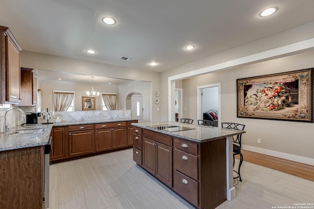 2106 W Gramercy Pl, San Antonio, TX 78201 - kitchen featuring visible vents, black electric stovetop, a kitchen breakfast bar, arched walkways, and a sink